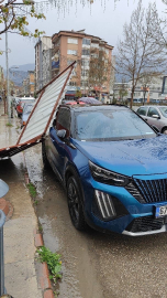 Fırtınanın etkisiyle yapıdan kopan parça araca zarar verdi