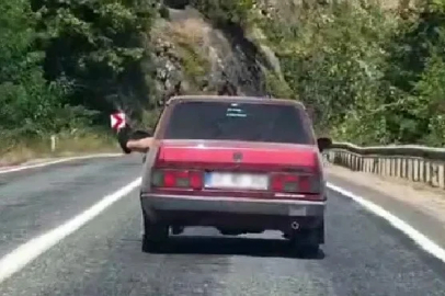 Ayaklarını camdan sarkıtarak trafiği tehlikeye attı
